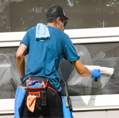 Un laveur de vitre vu de dos nettoyant une fenetre.